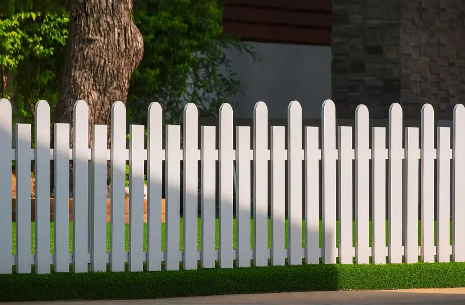A white plank fence on a lawn